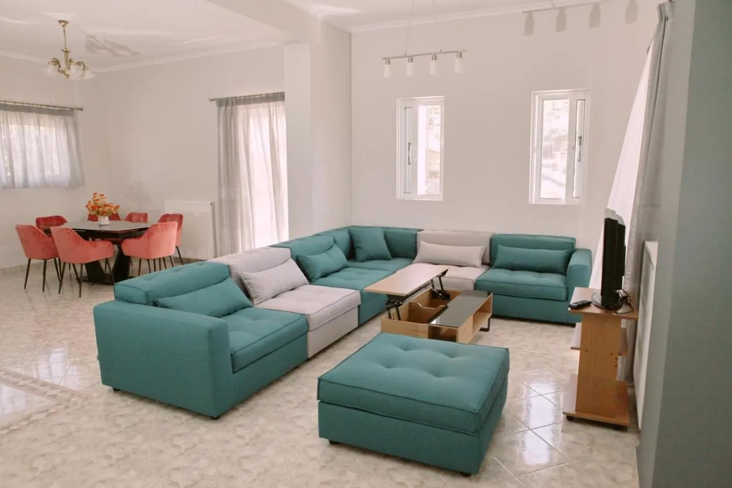 Σαλόνι με γαλαζοπράσινο γωνιακό καναπέ, μαρμάρινο δάπεδο και τραπεζαρία στο βάθος